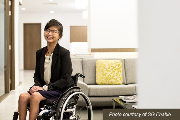 A young woman in a wheelchair dressed in professional attire and smiling confidently